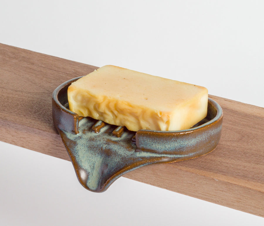 Bar of soap in a ceramic holder on a wooden surface
